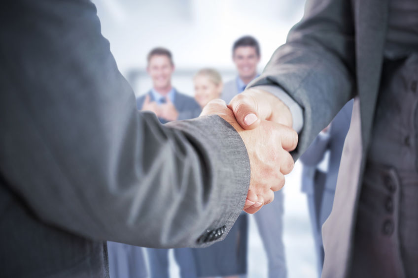 Composite image of business people shaking hands close up